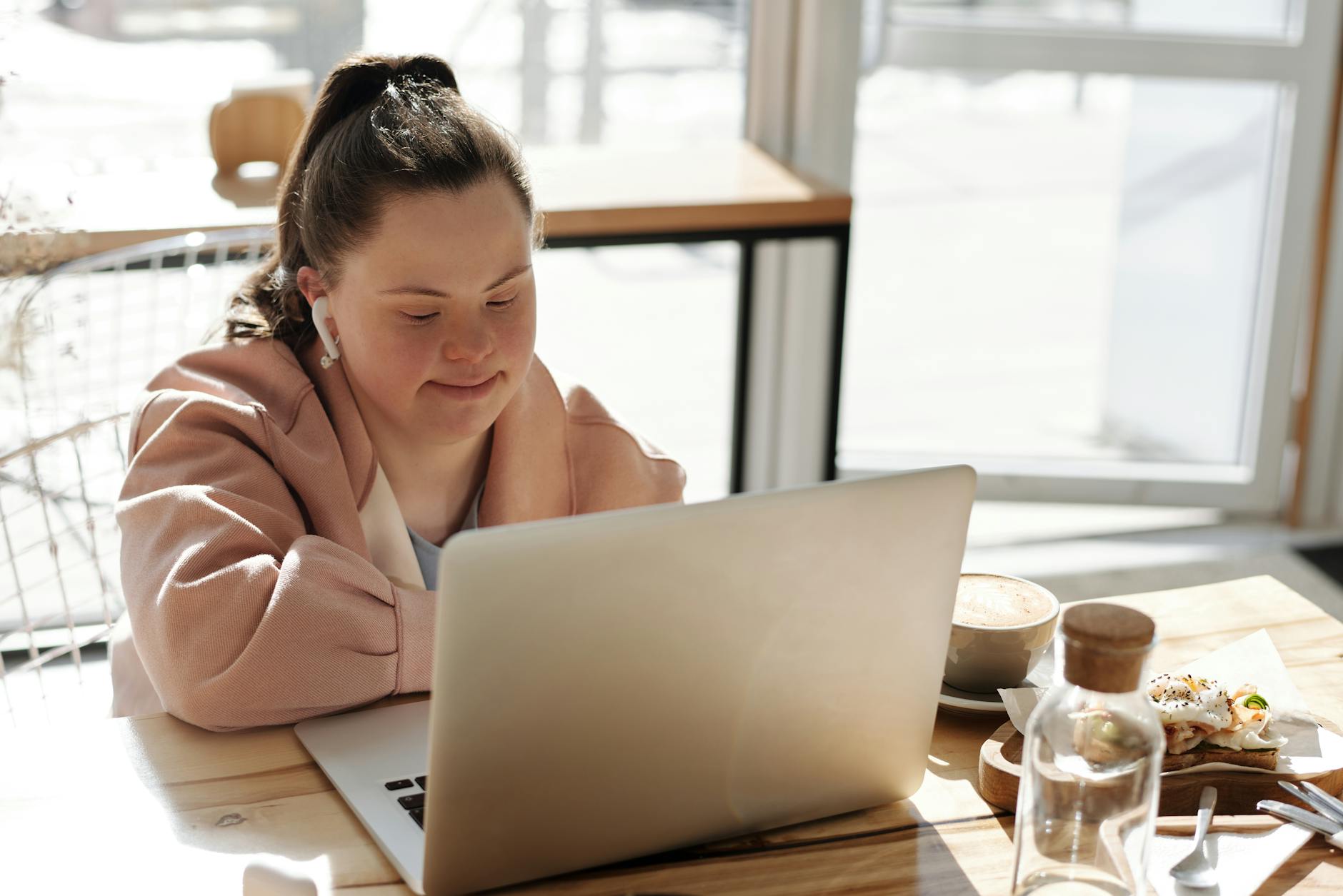 young girl using a laptop while having breakfast