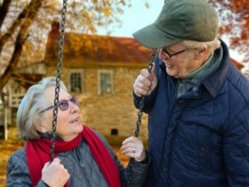 man standing beside woman on swing