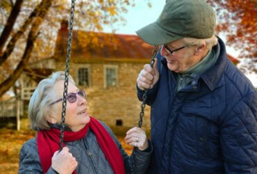 man standing beside woman on swing