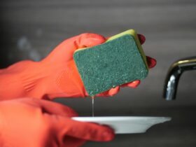 a person wearing rubber gloves while holding a sponge and ceramic plate