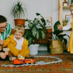 mother and two siblings playing with toy train at home