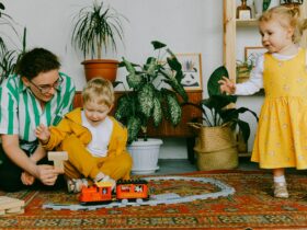 mother and two siblings playing with toy train at home