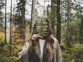 woman standing at woods holding green plant