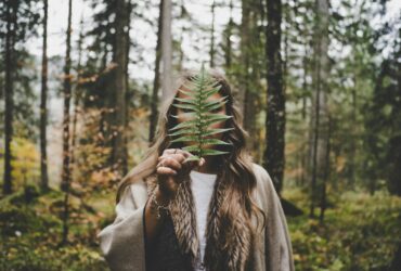 woman standing at woods holding green plant