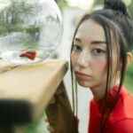 woman in red shirt looking at a fish bowl