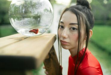 woman in red shirt looking at a fish bowl