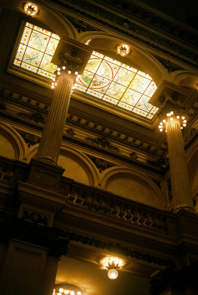 Low angle view of ornate columns and stained glass in Teatro Colón, Buenos Aires.